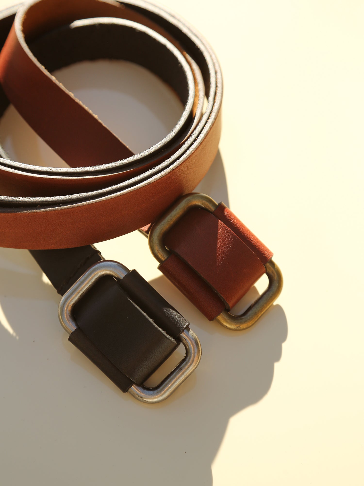 Saddle brown & black leather buckle belts close up