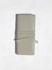 Light beige crocodile-embossed leather wallet with wrap-around strap closure, flat product shot