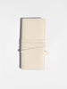 Ivory croc-embossed leather clutch bag closed with its wrap-around tie strap