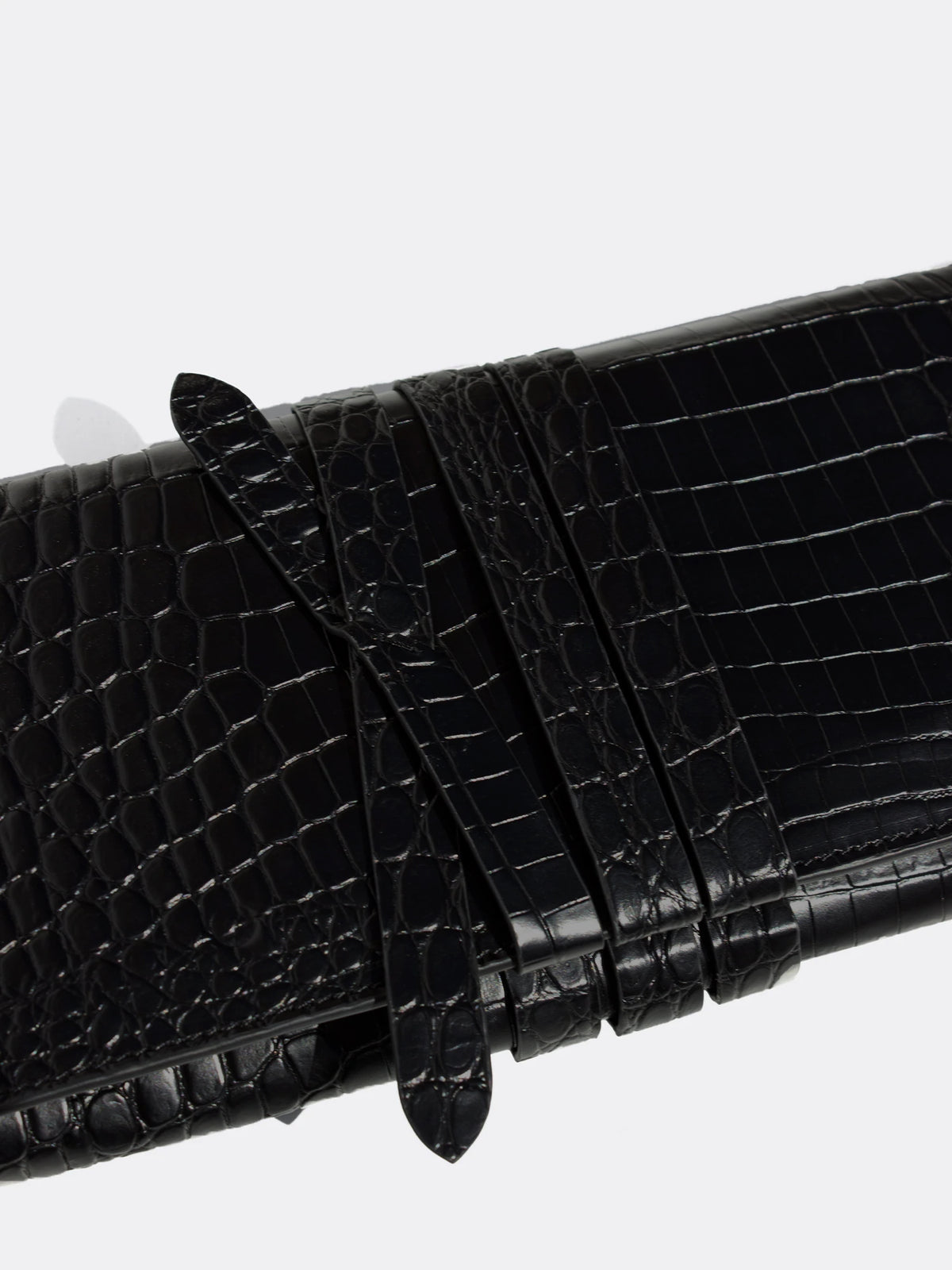 Close-up of the wraparound tie strap detail on a black crocodile leather clutch bag