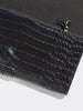 Close-up of a black crocodile-embossed leather clutch with gold ring pull detail