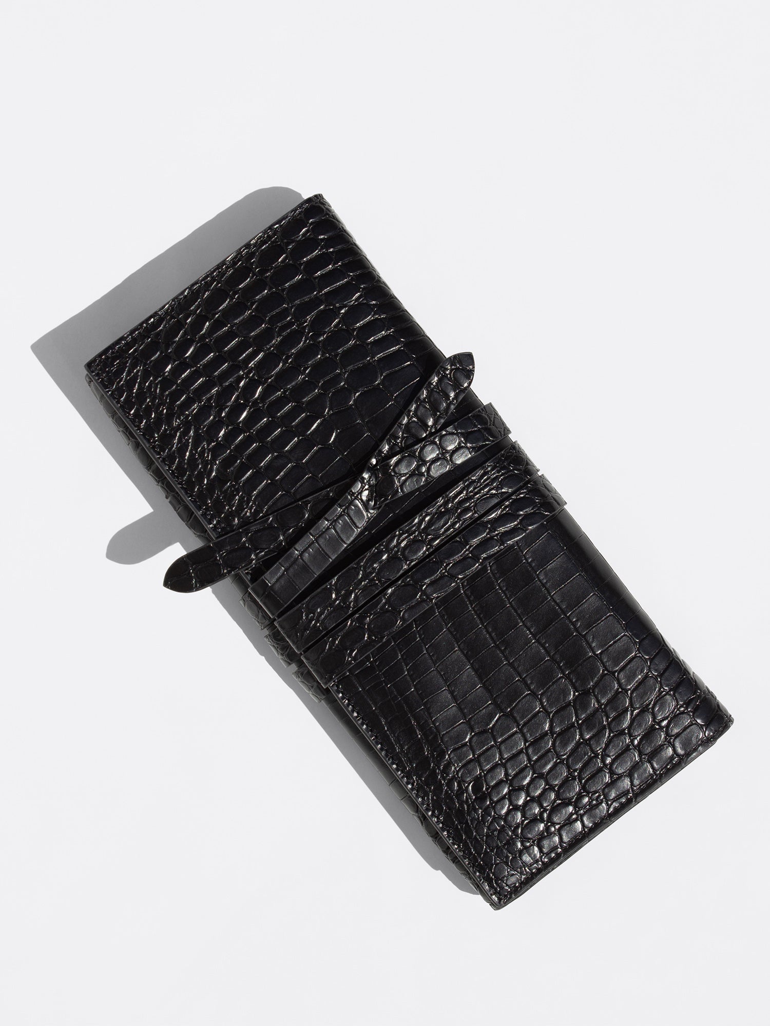 Black crocodile-embossed leather wallet with strap closure, flat product shot