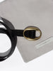 Close-up of a black crocodile-embossed leather belt with a gold oval buckle, resting on a Brochu Walker wallet pouch