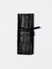 Black crocodile-embossed leather roll-up wallet with wrap strap closure, flat product shot