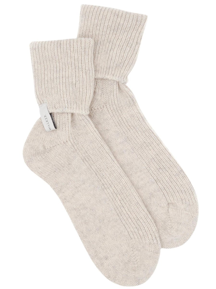 Pair of ribbed cashmere socks in mist mélange ivory with folded cuffs and cinched ankles.
