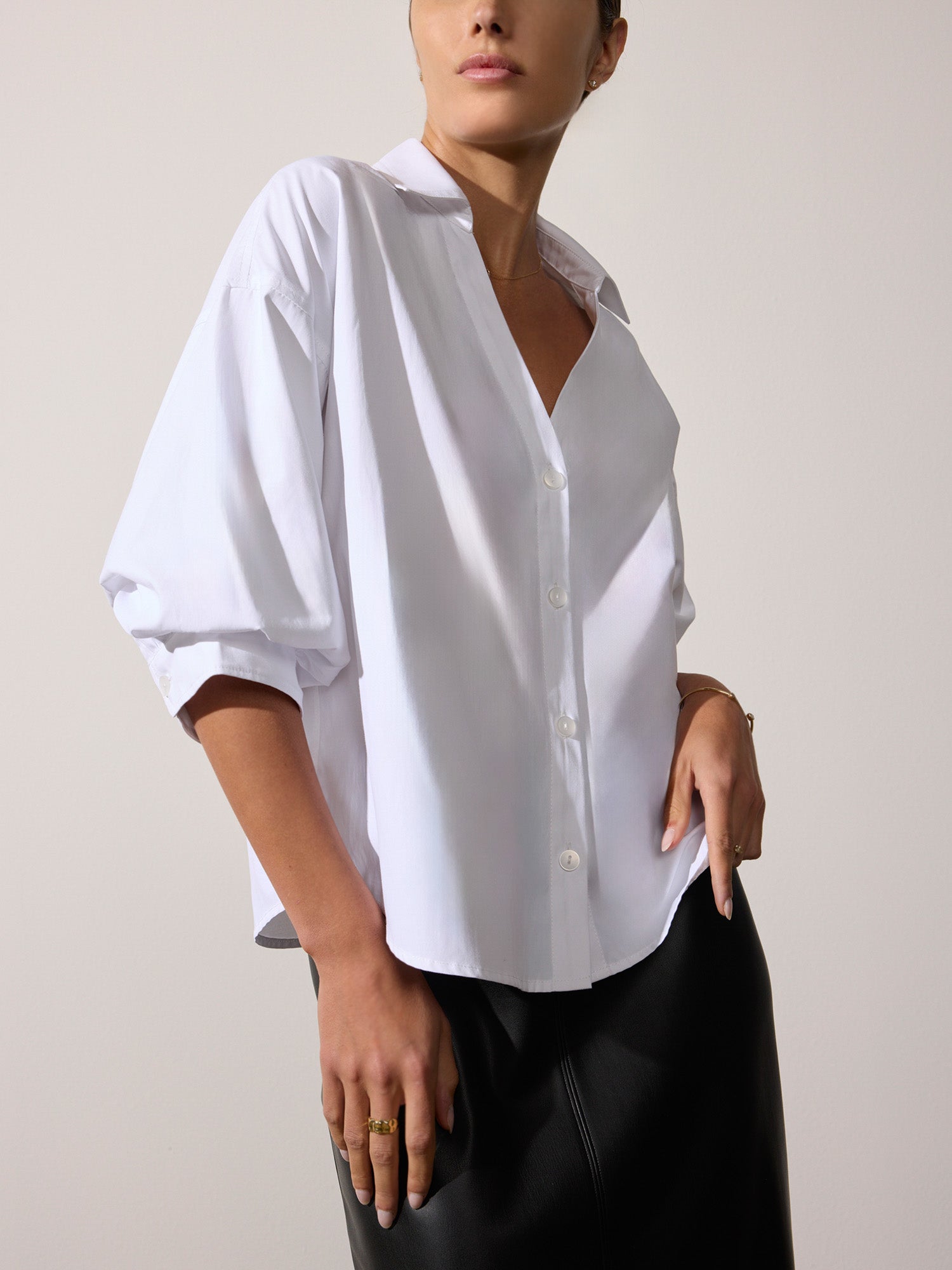 Woman modeling a women's white button-up shirt with puffed elbow sleeves and a black skirt