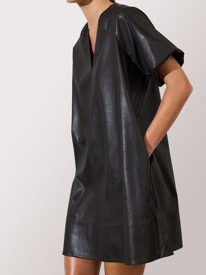 Black leather dress for women featuring short sleeves, a deep V-neck, and side pockets in a relaxed silhouette.