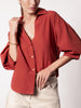 Button-up shirt in tuscany rust with voluminous puff sleeves, styled with beige bottoms