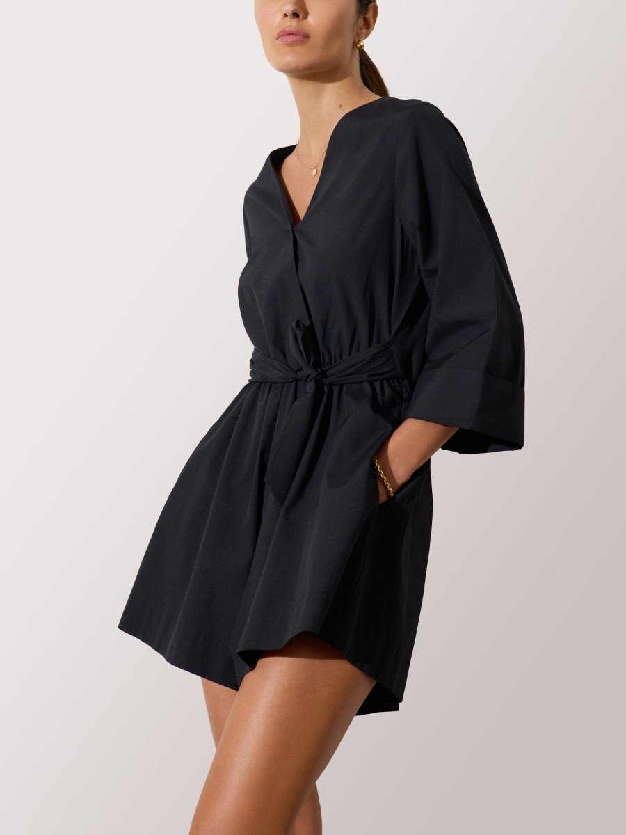 Black romper dress for women featuring a belted waist, V-neckline, and wide three-quarter sleeves for a modern silhouette.