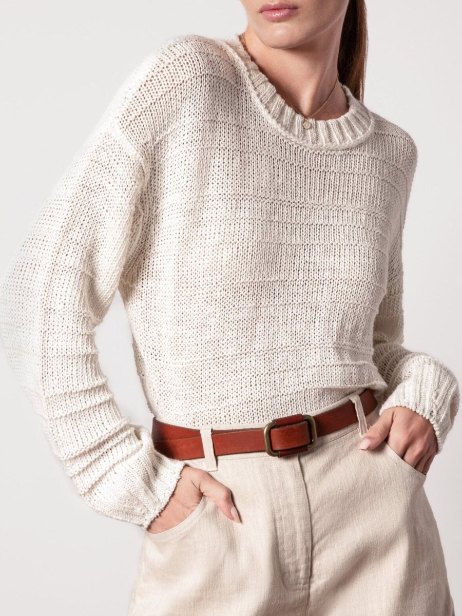White knit pullover for women featuring a relaxed fit, ribbed neckline, and lightweight texture styled with high-waisted shorts.