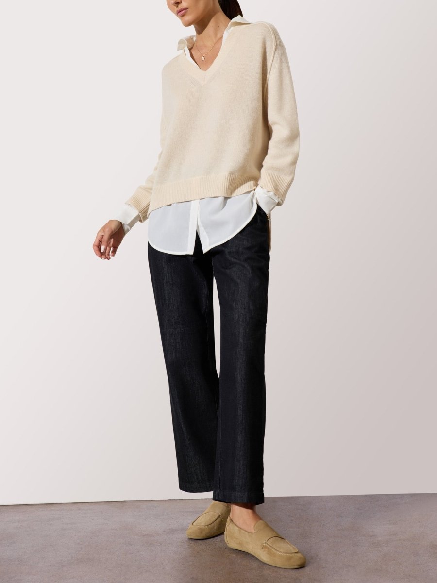 Cardigan sweater for women in a soft beige tone layered over a white button-up shirt with dark wide-leg pants.