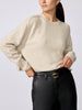 Woman wearing a cream cashmere crewneck sweater with black leather pants