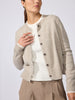 Woman wearing the Archie layered cardigan in gravel stone melange over a white ribbed top, paired with beige trousers.