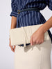 Cream crocodile-embossed clutch bag with a wraparound strap, held against a navy striped shirt and cream skirt.