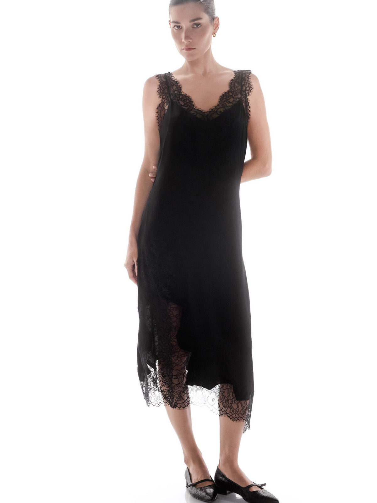 Woman wearing a black midi slip dress with lace trim at the neckline and hem against a white background
