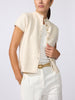 Woman wearing the Emmy short-sleeve cardigan in oatmeal melange with white trousers and a gold belt