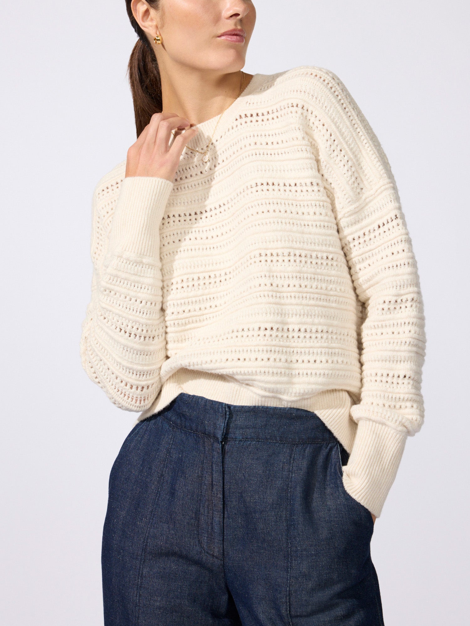 Woman wearing the Everyday multi-stitch bright crew sweater in oatmeal melange with dark blue trousers
