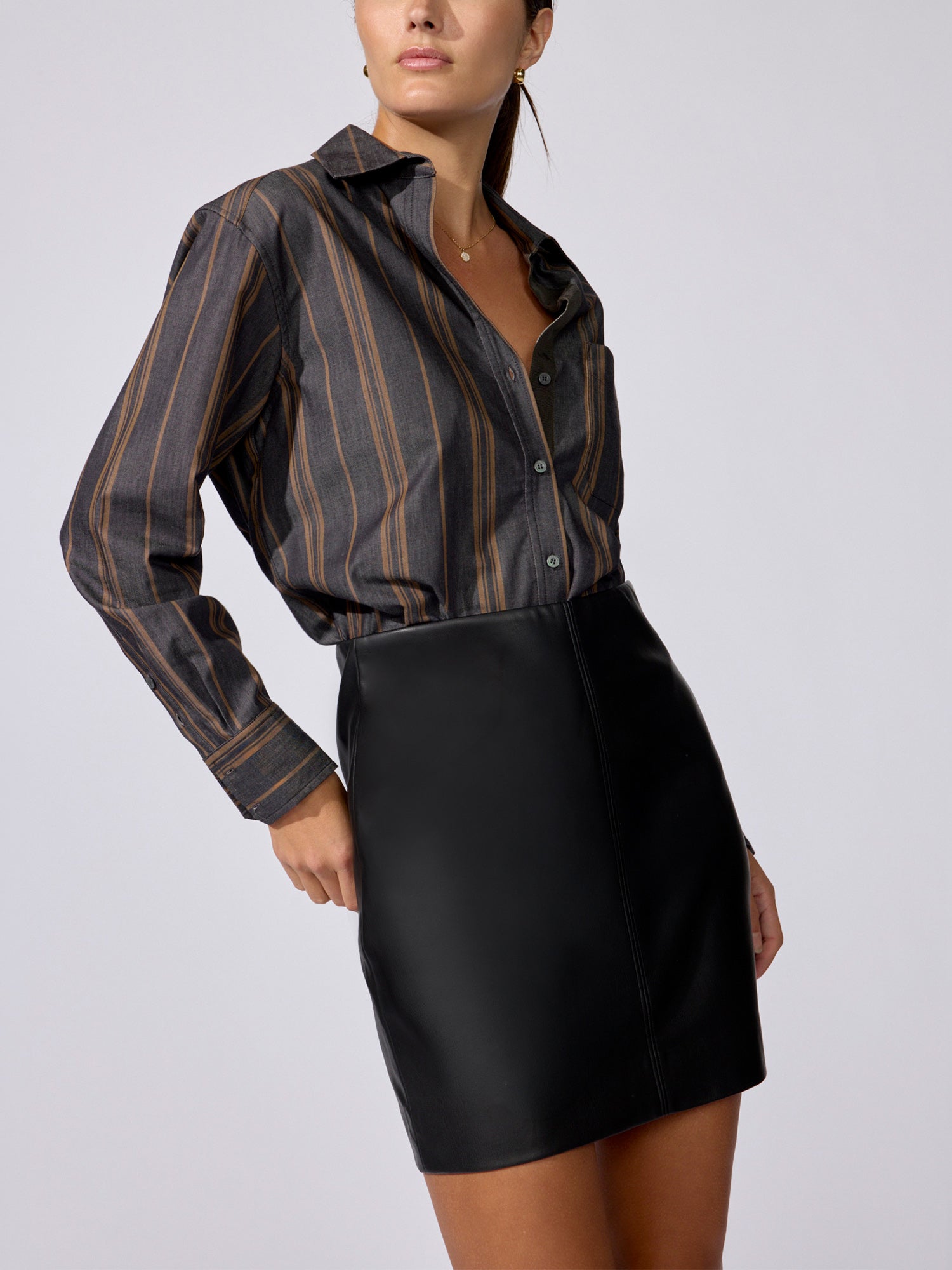 Woman wearing the Everyday shirt in Sedona stripe, tucked into a black faux-leather mini skirt