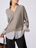 Woman wearing the V-neck pullover in otter melange with flint stripe, layered over a striped button-down with black pants and a leather tote bag.