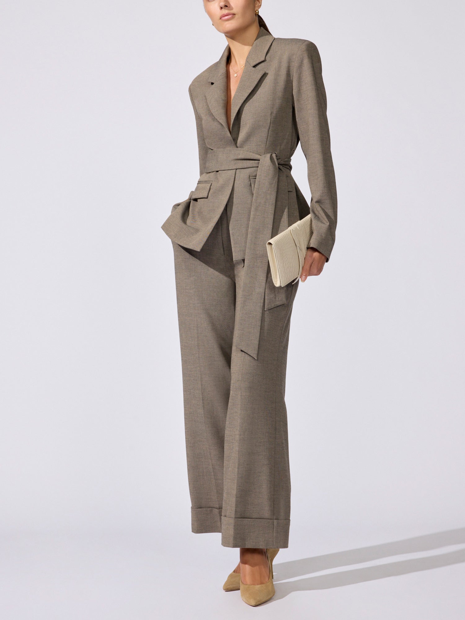 Full-length view of the Lincoln blazer in gravel melange, belted, with matching wide-leg trousers and a beige clutch