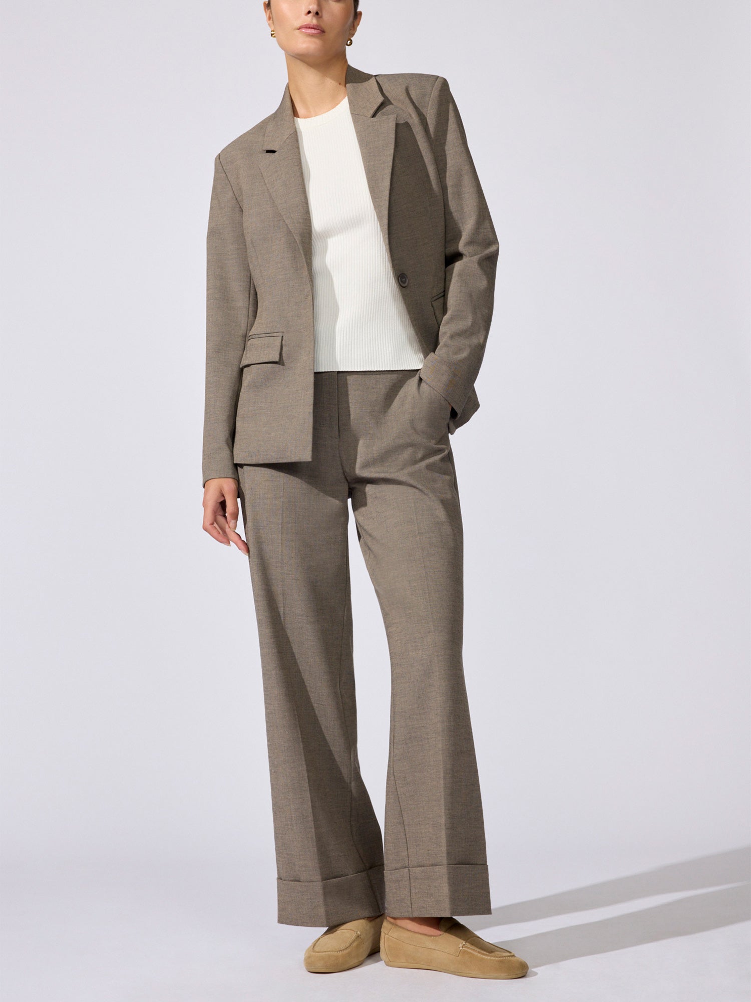 Woman wearing the Lincoln blazer in gravel melange over a white top, with matching trousers and tan loafers