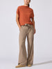 Woman wearing the Morten funnel neck cashmere top in canyon orange melange with beige wide-leg drawstring trousers, standing