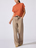 Full-length view of the Morten funnel neck cashmere top in canyon orange melange with beige wide-leg trousers