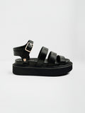 Black leather sandals with three padded straps, a gold ankle buckle, and a chunky platform sole shown in a full side profile.