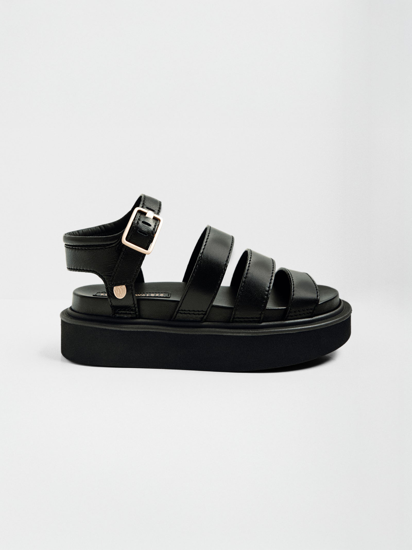 Black leather sandals with three padded straps, a gold ankle buckle, and a chunky platform sole shown in a full side profile.