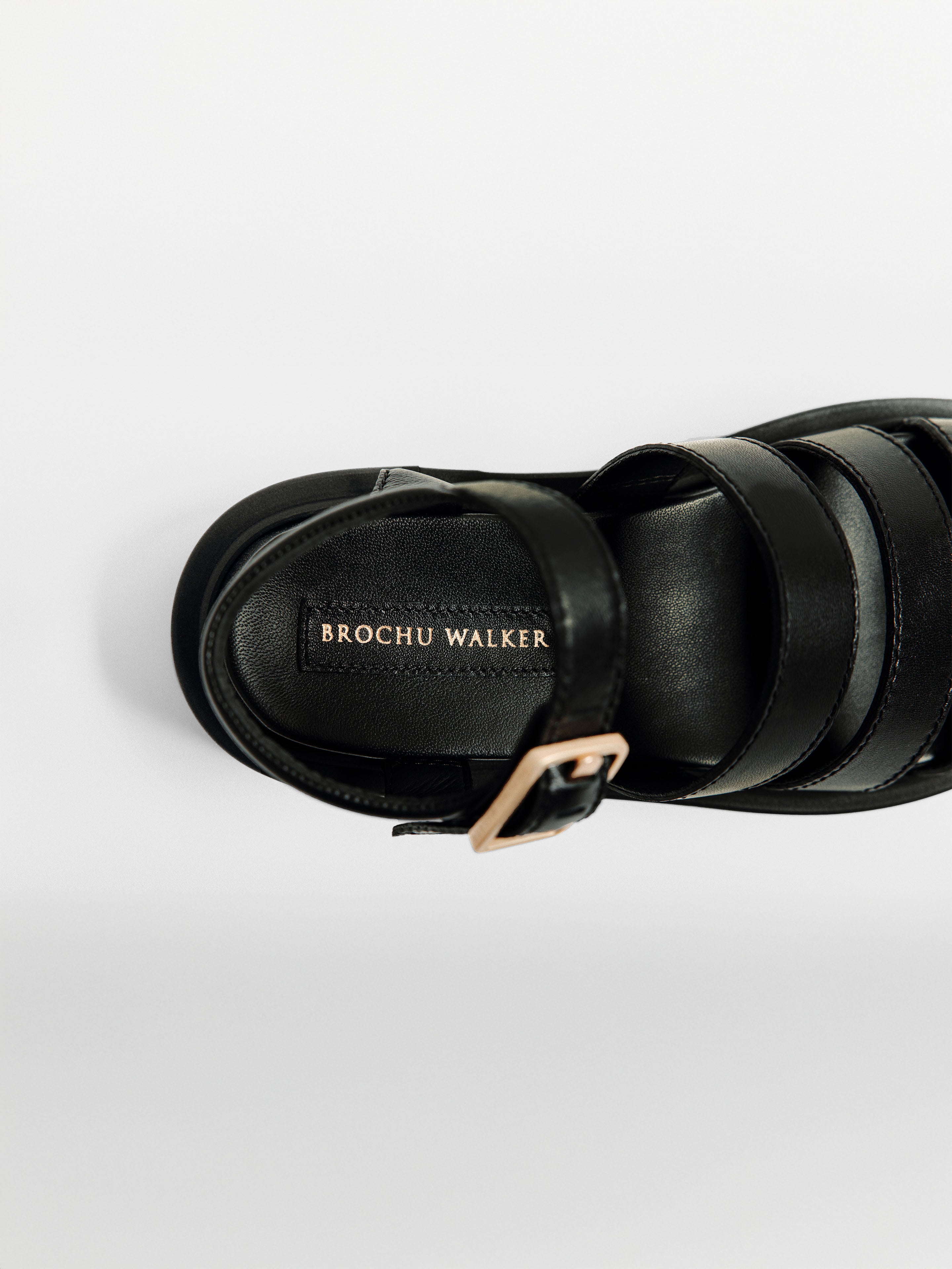 Black strappy sandals with a padded footbed, gold buckle ankle strap, and Brochu Walker branding shown from a top-down view.