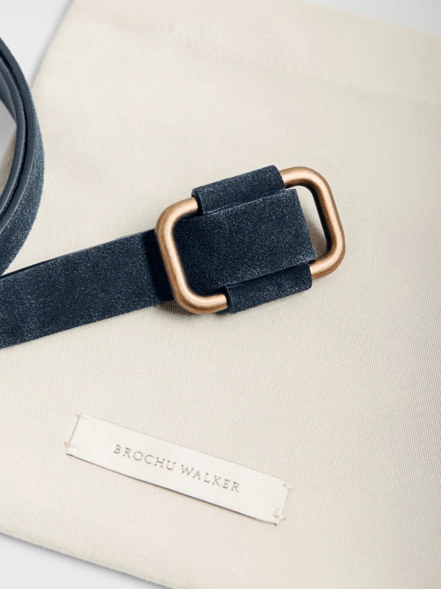 Classy belt in dark navy suede with a brushed gold rectangular buckle displayed on a cream Brochu Walker dust bag.