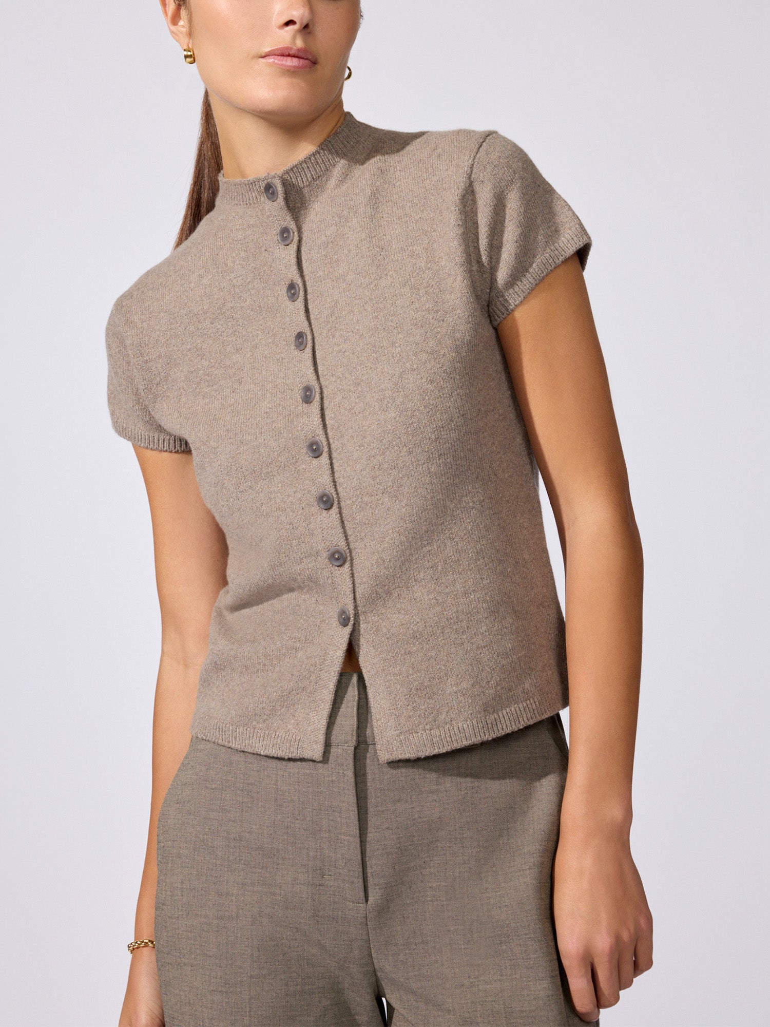 Woman wearing the Emmy cotton-wool cardigan in otter melange, a short-sleeve knit button-front top styled with matching knit trousers.