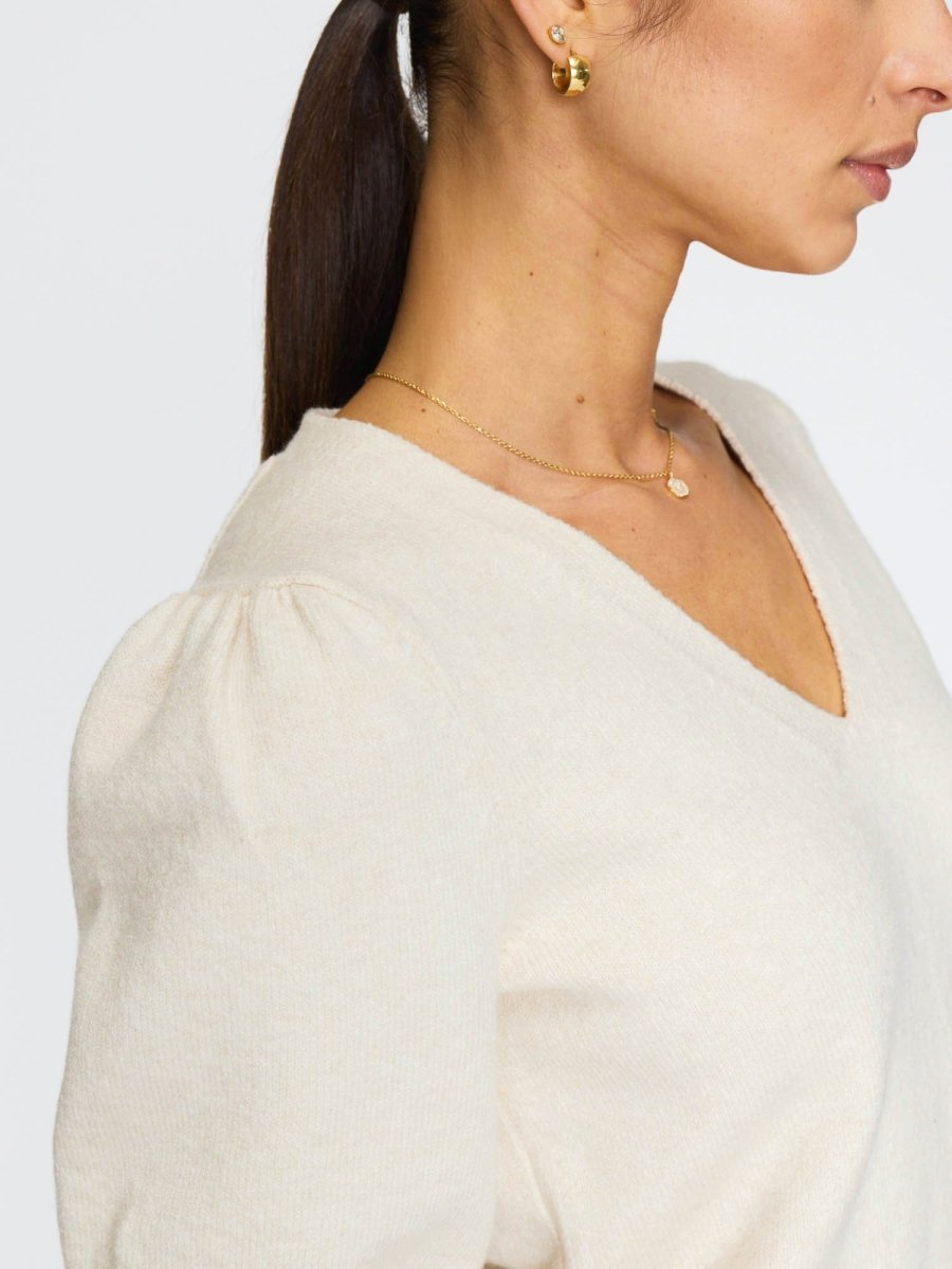 Deep V-neck women's sweater in ivory with soft puff sleeves and subtle ribbing at the cuffs.