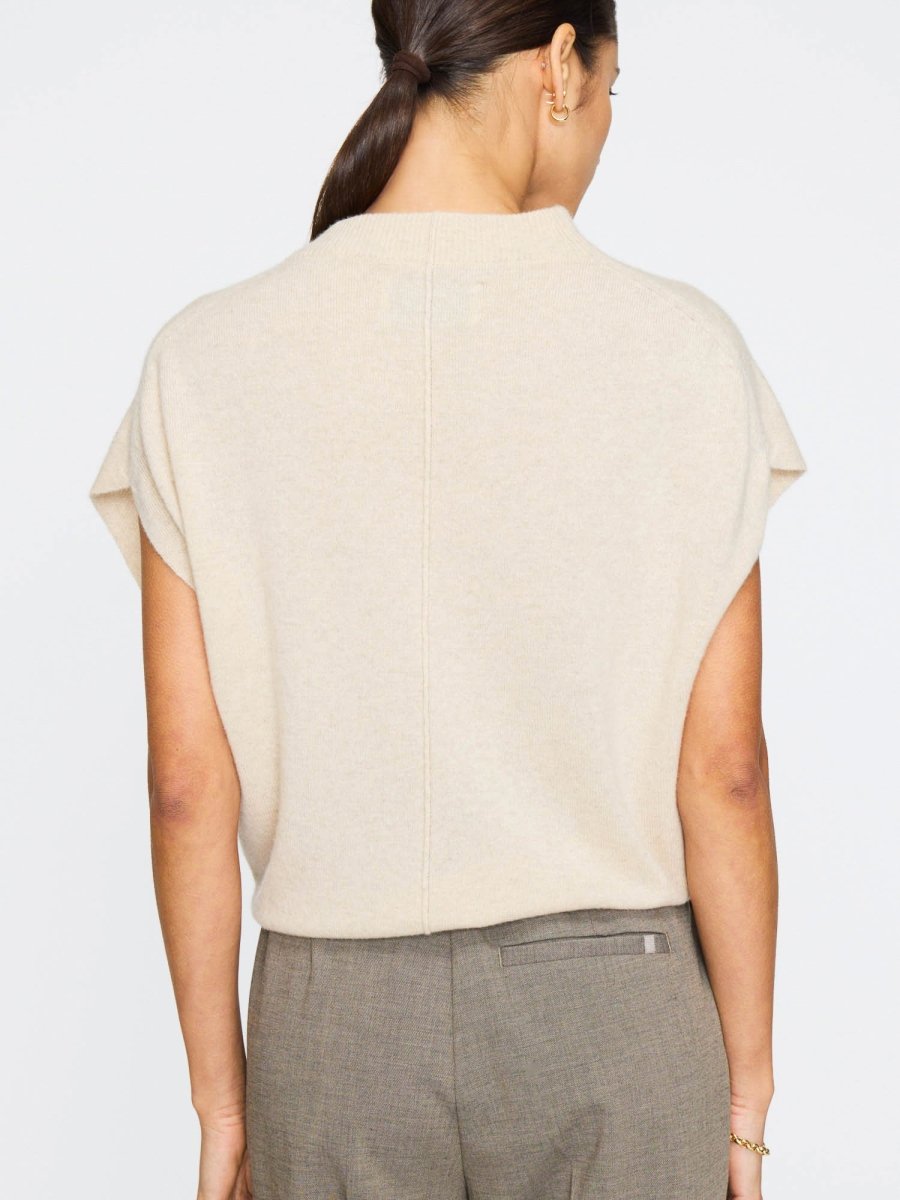 Sleeveless cashmere top for women in light beige with a mock neck and a relaxed fit over tailored pants.