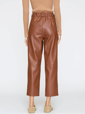 Women's brown vegan leather pants with a high waist and wide cropped legs, paired with beige suede loafers.