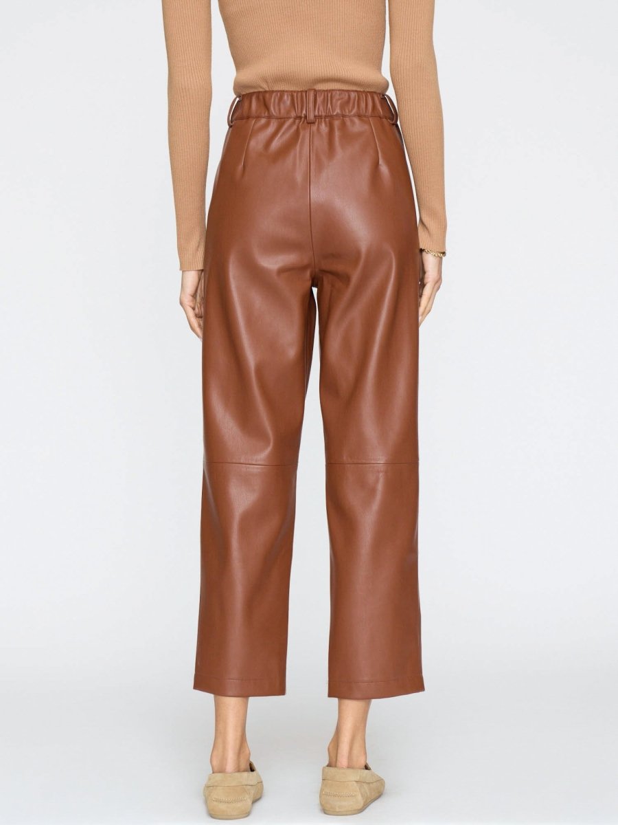 Women's brown vegan leather pants with a high waist and wide cropped legs, paired with beige suede loafers.