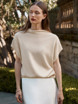 Women's cashmere top in soft cream with a draped funnel neck and sleeveless silhouette.