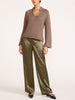 Full-length view of a woman wearing olive green satin pants with a taupe knit sweater and black flats