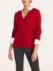 Woman wearing a women's red v-neck sweater with white shirt collar and cuffs, styled with dark gray leggings
