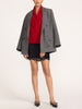 Full-length view of a woman in a women's black lace mini skirt styled with a red cowl neck top, gray double-breasted blazer and black flats