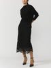 Women's black lace midi skirt with scalloped hem styled with a black knit sweater and ankle-strap heels