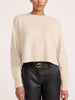 Women's cream cashmere crewneck sweater styled with black leather pants and a gold buckle belt
