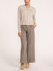 Full-length view of a woman wearing the Brochu Walker Archie Layered Cardigan in Gravel Stone Melange, styled with wide-leg taupe trousers and beige slip-on shoes.