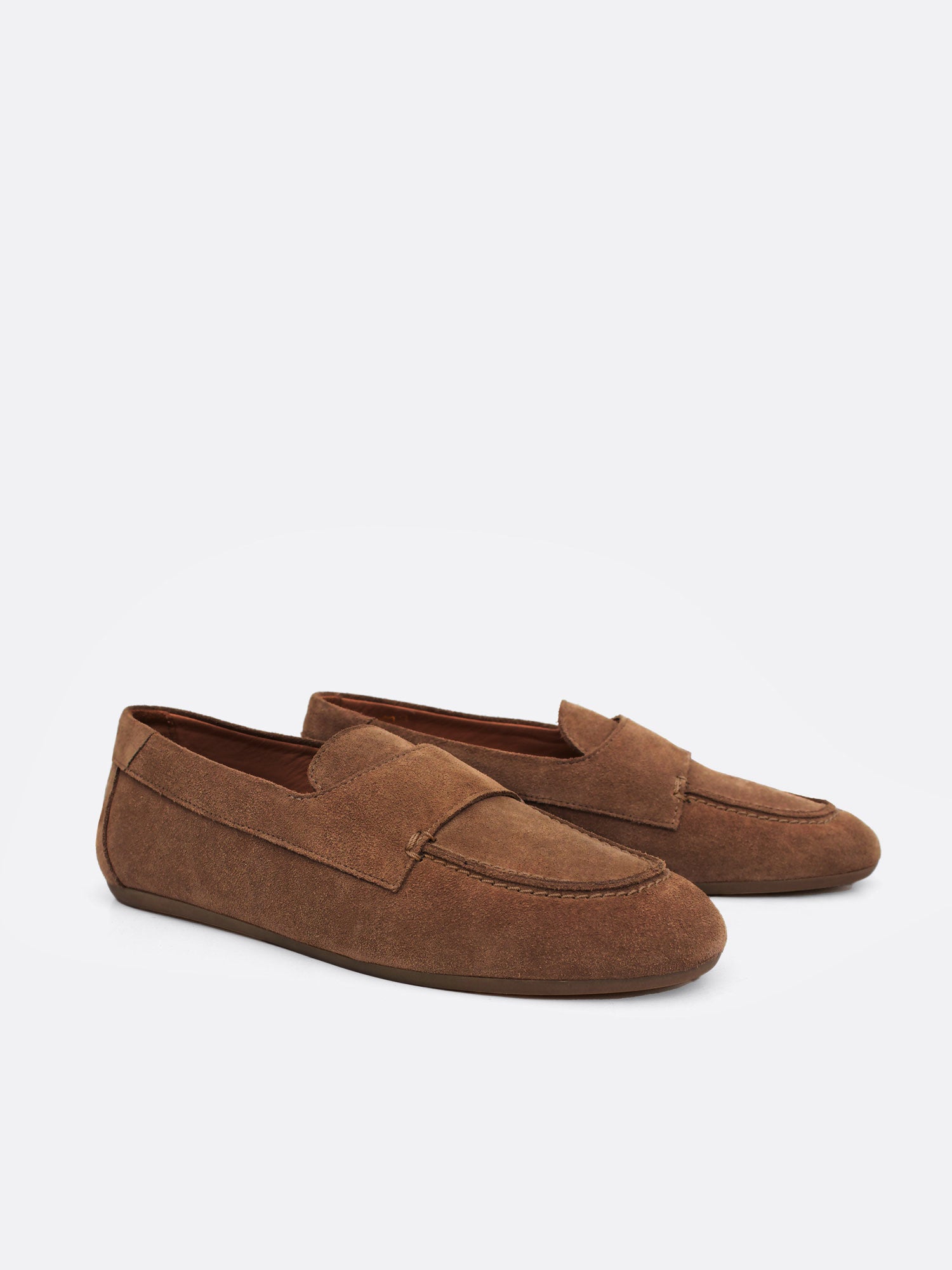 Angled view of a pair of tan suede loafers with low rubber soles on a white background.