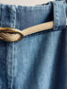 Classy belt in tan suede with a gold oval buckle threaded through light-wash denim trouser loops shown in close-up detail.