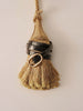 Black crocodile-embossed leather belt with gold buckle, wrapped around a jute tassel