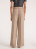 Back view of a woman wearing the Brochu Walker Duke Suit Pant in Tawny, high-waisted wide-leg trousers styled with a gray top and beige heels.