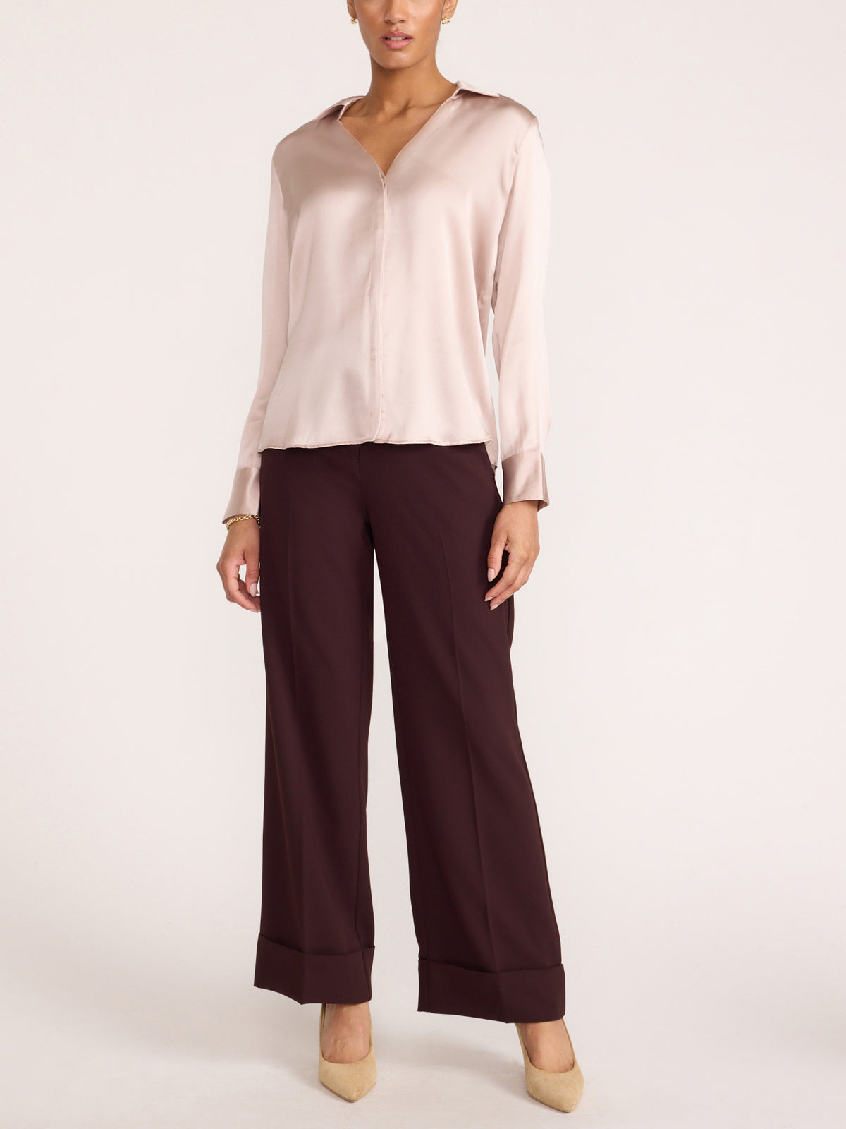 Women's blush pink satin blouse with long sleeves, full-length view with wide-leg brown trousers and beige heels