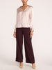 Women's blush pink satin blouse with long sleeves, full-length view with wide-leg brown trousers and beige heels