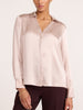 Women's blush pink satin V-neck blouse with long sleeves, close-up view styled with brown trousers